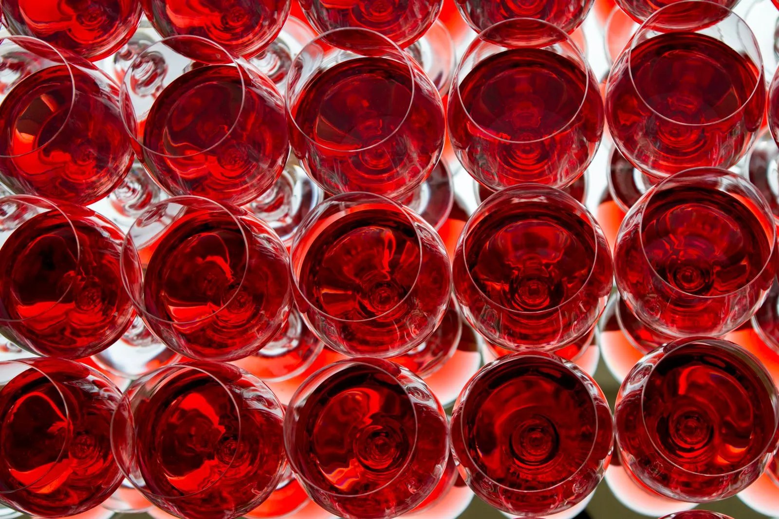 A captivating top-down view of multiple red wine glasses with a striking mirror reflection.